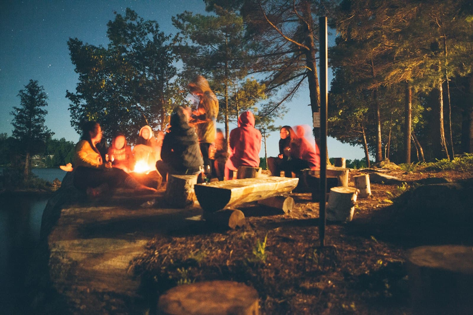 Team gathered around a lakeside campfire at night